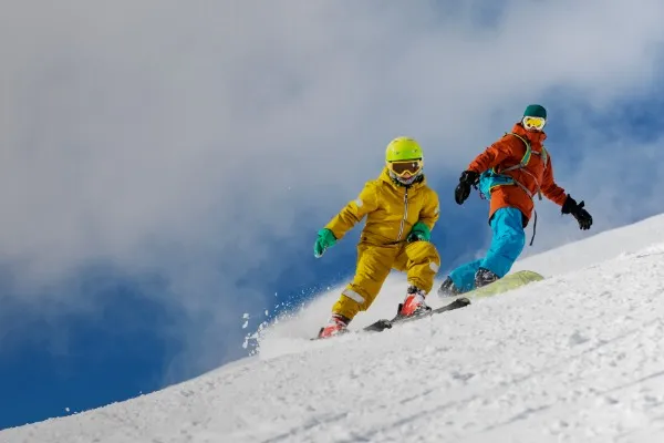 dos personas esquiando y haciendo snowboard en una pista nevada